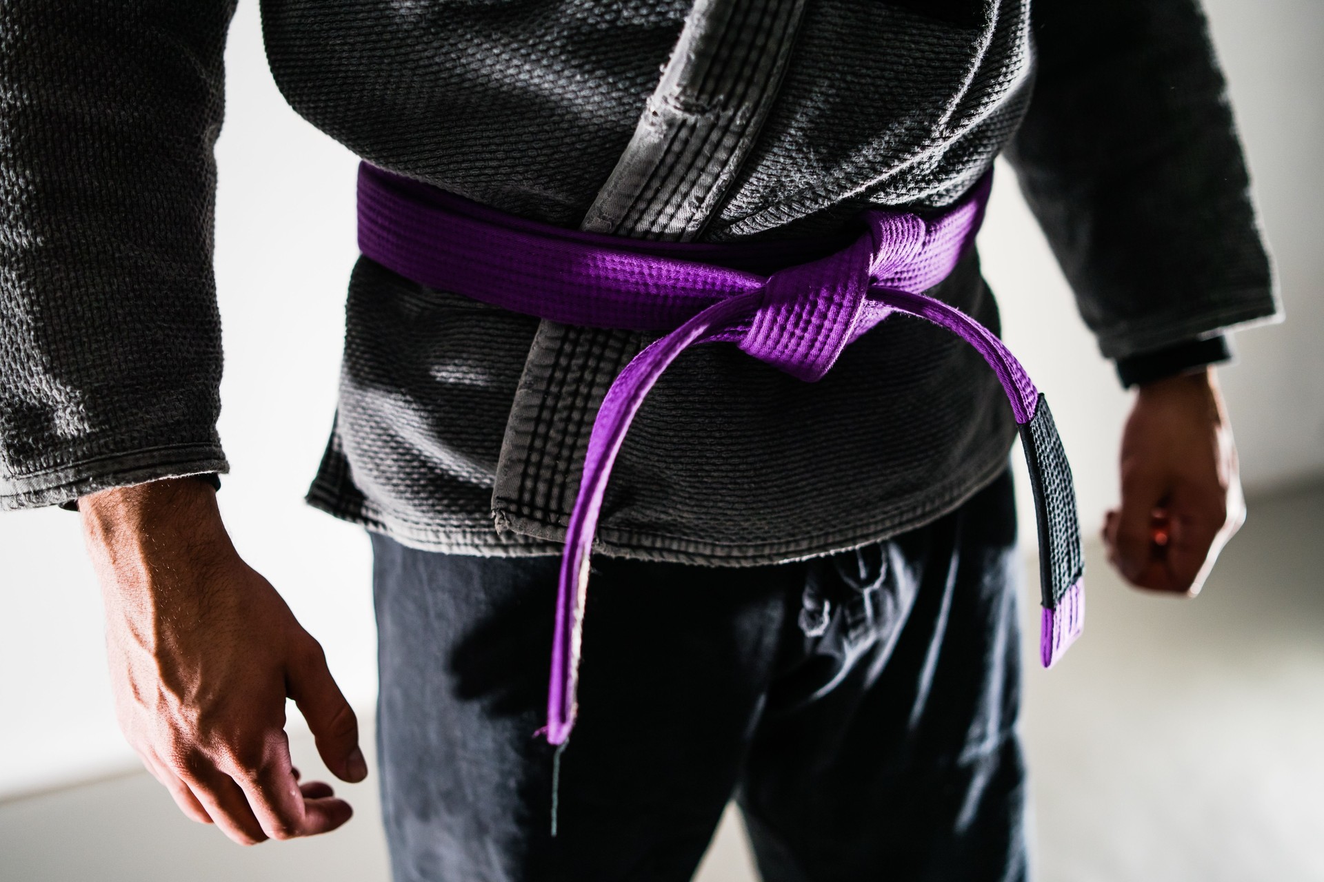 Close Up on Midsection Of A Brazilian Jiu JItsu BJJ fighter with purple belt in a black gi kimono